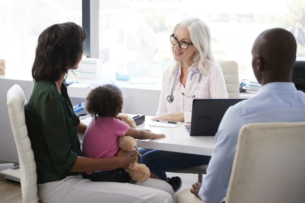 Family With Daughter In Consultation With Doctor In Office
