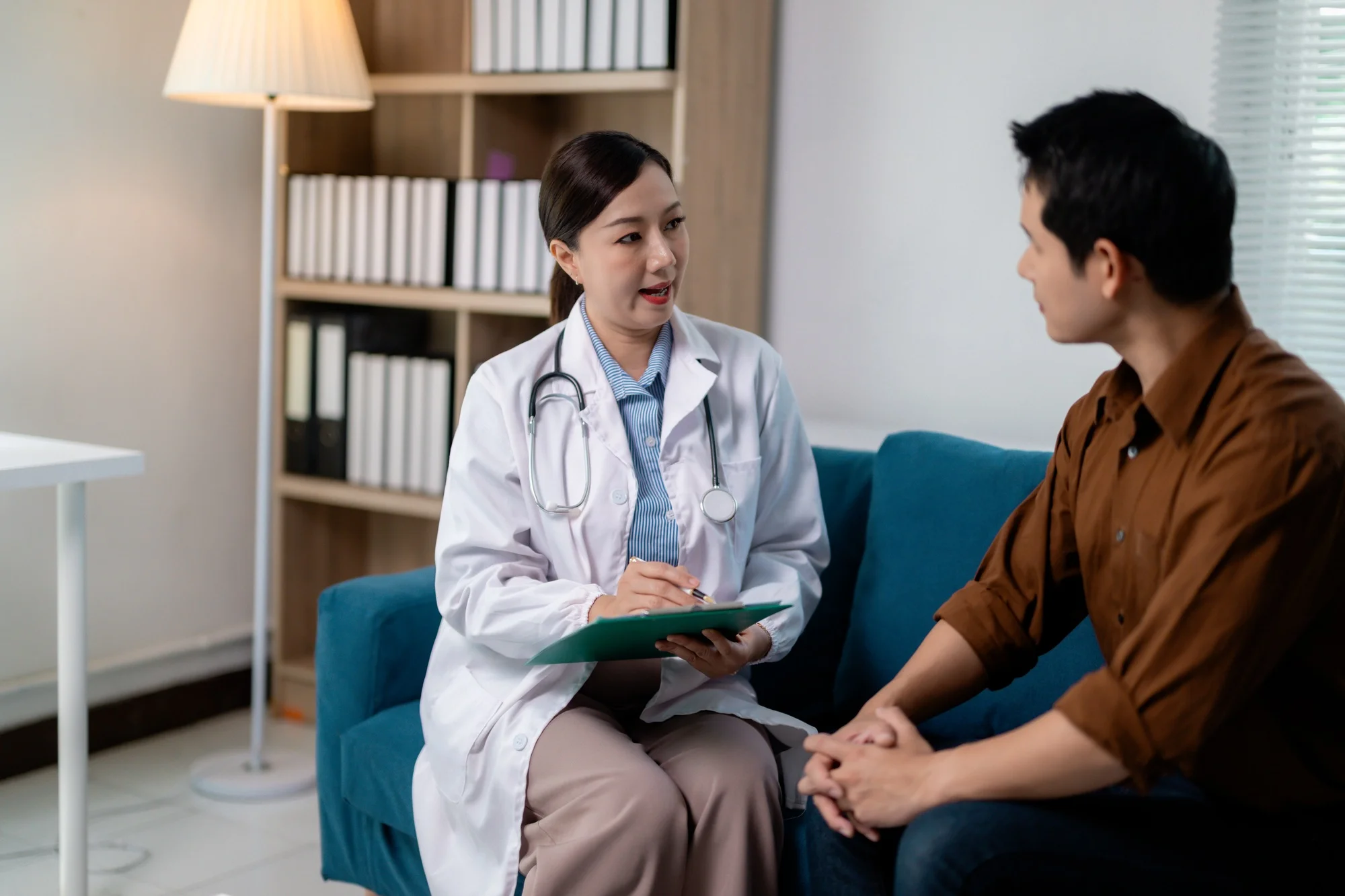 Female doctor taking notes while interviewing patient in clinic