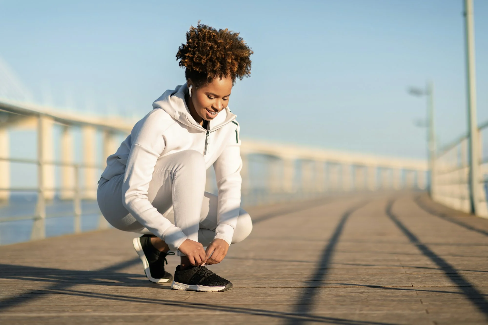 Running Shoes. Black Female Tying Shoe Laces Before Jogging On Pier Outdoors