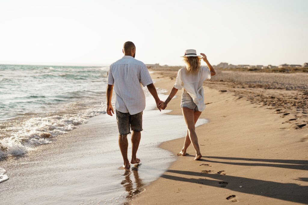 Young beautiful couple walking on beach near sea